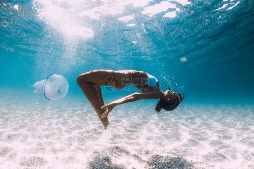 女潜水员与水母一起在沙海上滑翔图片