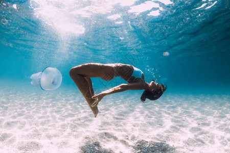 女潜水员与水母一起在沙海上滑翔图片