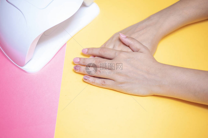 一名年轻女子在手术后修剪双手使用虫胶uvled灯的漂亮女孩指甲油艺术图片