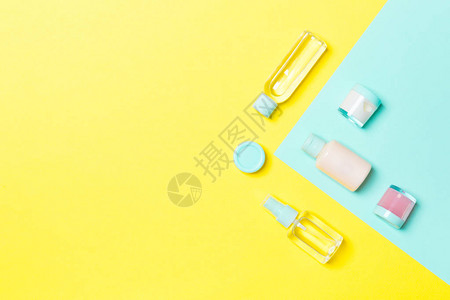 黄色和蓝色背景的不同化妆品瓶和化妆品容器的顶部视图具有复制空图片
