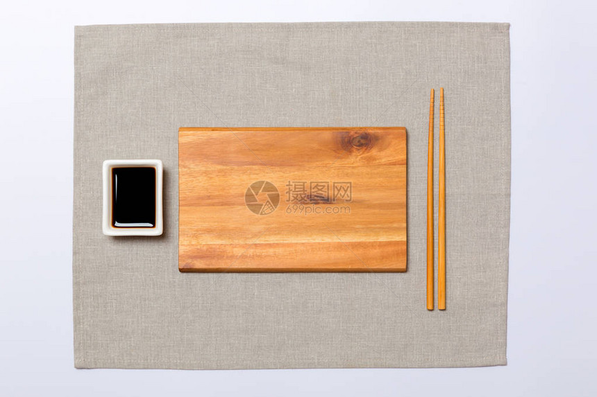 灰色餐巾背景上带筷子的空长方形棕色木盘图片