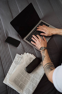 在家附近床上用手机报纸和眼镜盒在笔记本电脑上工作的男人手纹图片
