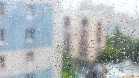 窗玻璃上的雨滴和秋天下雨日背景的模糊房图片