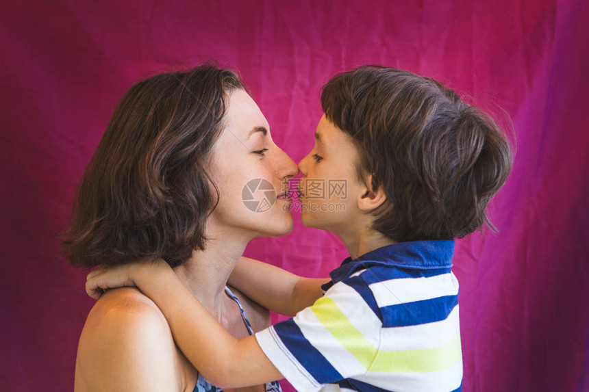可爱的男孩亲吻和拥抱妈一个带着孩子的女人的画像棕色眼睛的男孩在耳图片