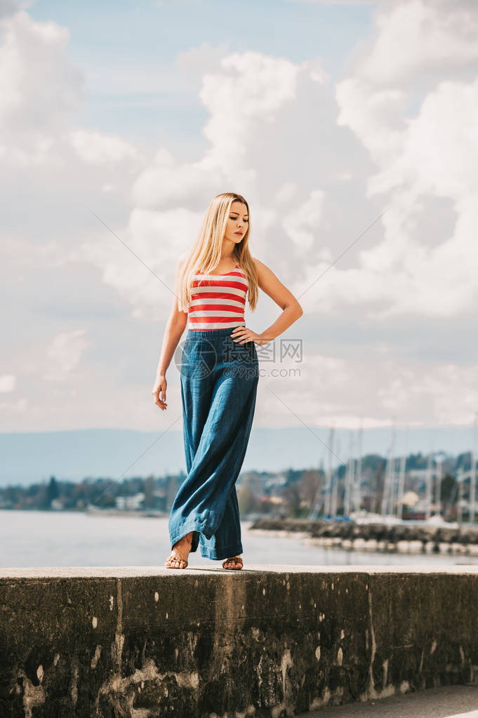 身着红白条纹背心和双腿牛仔裤的湖边年轻美女外图片