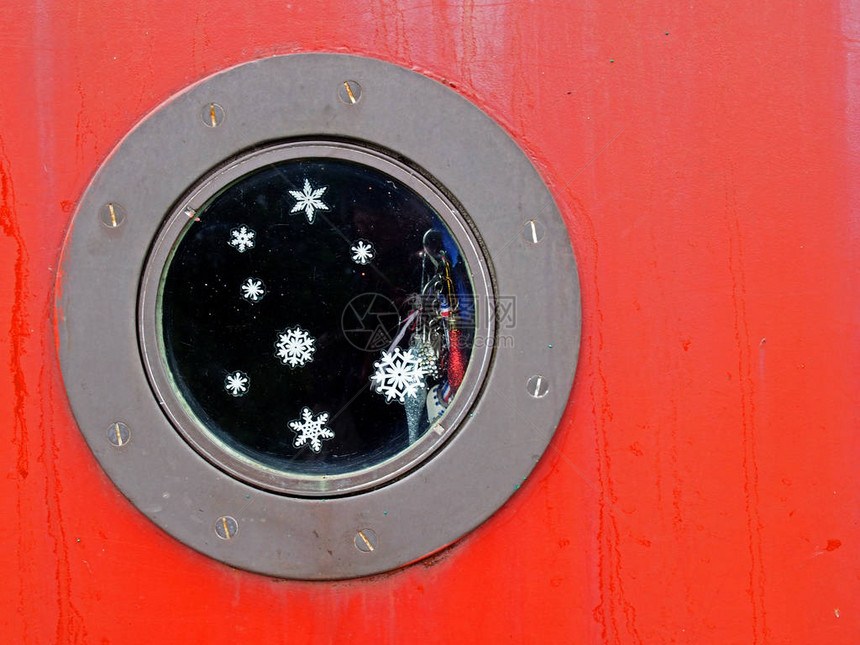 紧贴着红船的圆金属洞口窗子里有雪花和闪光片还有闪亮的图片