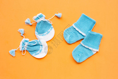 橙色背景上的婴儿手套和袜子顶视图图片
