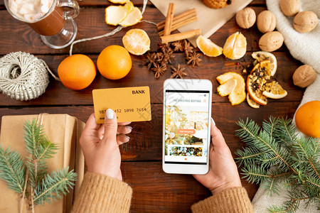 以塑料卡和智能手机在木桌上用圣诞礼物针具和水果制作图片