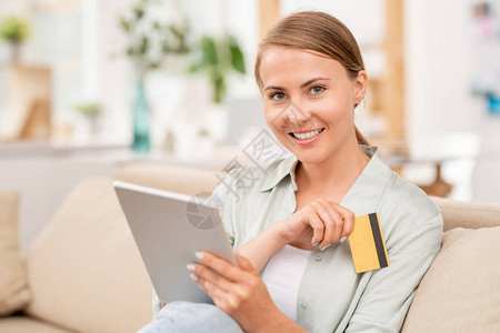 年轻女客户使用触摸板搜索在线商品和塑料卡以付费图片