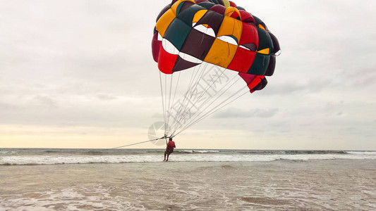 日落时在海滩上进行滑翔伞极限运动图片
