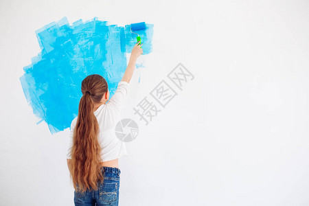 女快乐女孩用蓝油漆在墙上涂彩图片