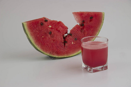 一片西瓜和一杯白色背景上的果汁图片