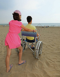 小女孩把轮椅推到沙海滩上夏天有个小图片