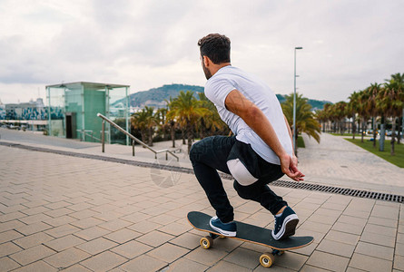 滑板手在现代城市街道上骑滑板图片