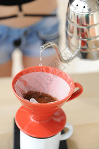 鹅颈管女孩咖啡师冲泡咖啡滴水法将鹅颈水壶中的水倒入红色hariov60漏斗中背景