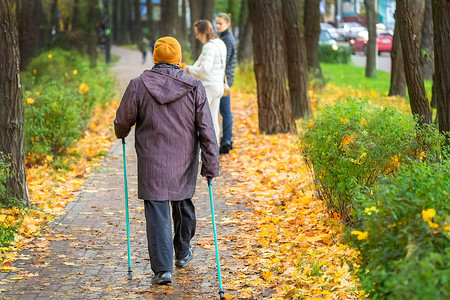 在美丽多彩的秋季公园享受北欧式行走的高级女老年人在户外做撑杆步行锻炼老年背景图片