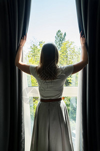 女人早上在酒店房间打开窗帘图片
