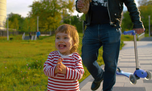 小女婴在公园里走着父亲穿着摩托式夹克的粗鲁父亲图片