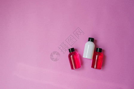 粉红色背景上用于化妆品淋浴胶洗发水和头发润滑剂的小旅行小瓶的顶部成分图片