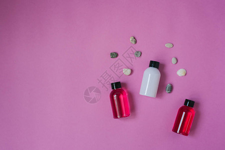 百年润发粉红色背景上用于化妆品沐浴露洗发水和润发膏和海卵石的小旅行瓶的顶视图组成具有复制空间的身体或背景