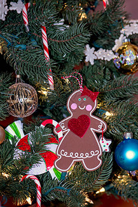 一位装饰的姜饼女人挂在多彩的圣诞树上图片