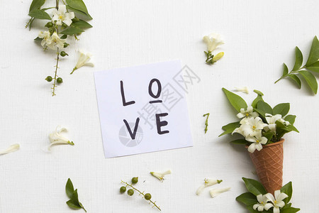 用白色花朵加茉莉的白花在锥形安排中的情爱贺卡笔迹以背景白色为平图片