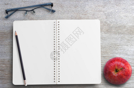 办公室办公空间木制桌上空页玻璃铅笔和红苹果的开放笔图片