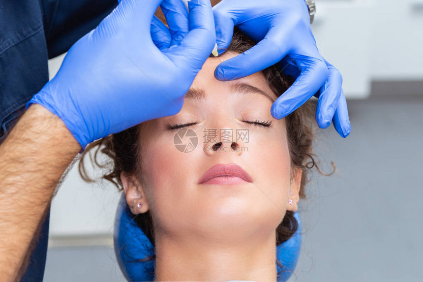 有魅力的年轻女人正在接受面部注射她平静地坐在诊所里专业美容师正在用透明质酸图片