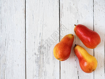 3个成熟的红梨对白木背景图片
