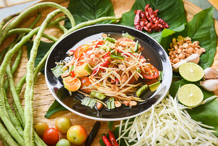 木餐桌上供应木瓜沙拉盘子上供应青木瓜沙拉辣泰国菜图片