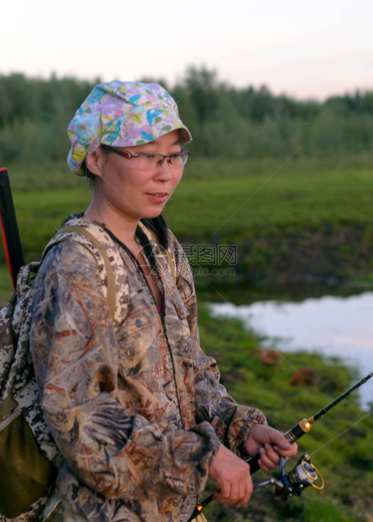 YakutAsiaAsian女孩与观光渔民小心翼地把钓鱼网的把手转向日落时北河流域图片