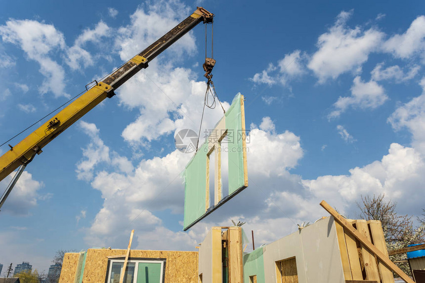 使用复合吸水板建造新的和现代模块式房屋的过程用蓝色天空背景的墙壁部图片