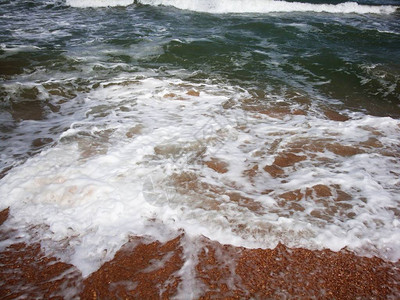 沙滩上的小海浪泡沫波在沙滩的金图片