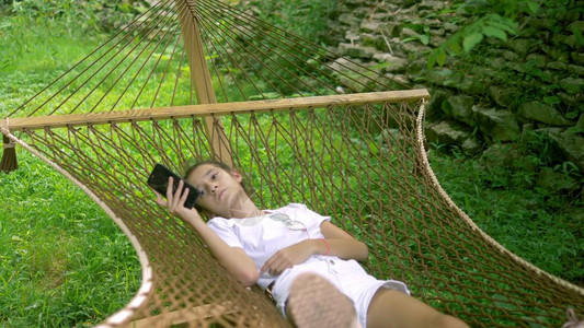 少女在森林野餐时躺在树下吊床里的时候用图片