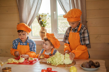 三位年轻厨师在乡间别墅的桌子上切蔬菜做素食汤西装厨三兄图片