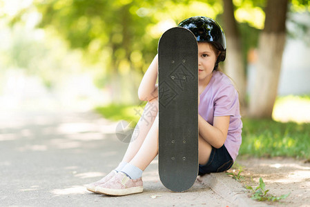 戴头盔的小女孩坐在滑板后面躲藏不管图片