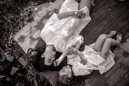 母亲和女儿在外出时躺在森林里的老长凳上黑白图图片