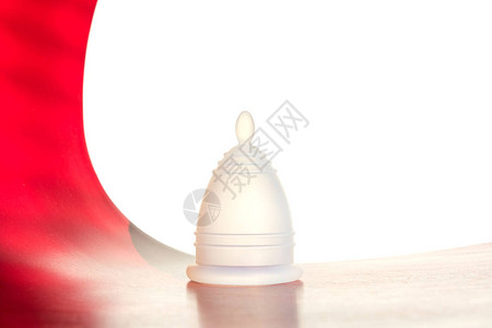 白色红背景上的白色可重复使用月经杯在关键日子代替棉签的女卫生替代产品图片