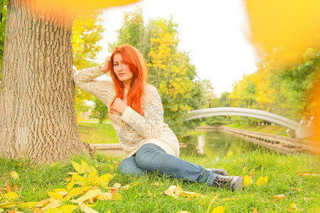 穿着长橙色红发的时装女士在秋图片
