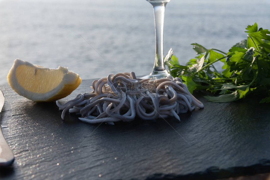 在石桌上放着柠檬一束芹菜和一杯葡萄酒的熟鳗鱼图片