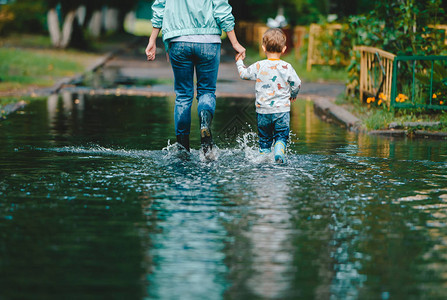 一个女人带着她的孩子去大水坑里后视图夏季阴雨天气概念图片