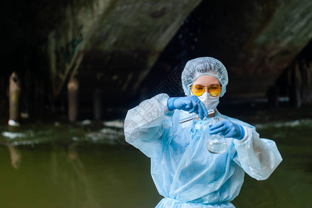 使用试管的女生物化学家或传染病专家对来自城市河流的水图片