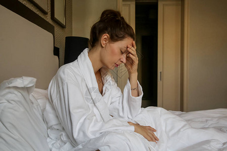坐在床上的年轻悲伤妇女忧郁焦虑关系困难偏头痛图片