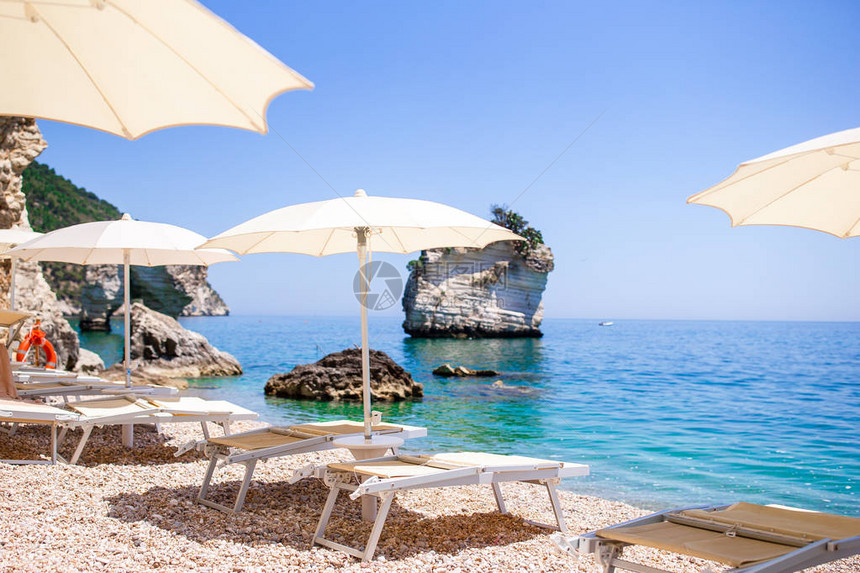 欧洲海滨白色沙滩上的白色日光浴床和遮阳伞图片