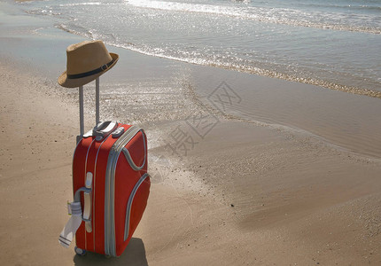 红色手提箱站在海边的沙滩上图片