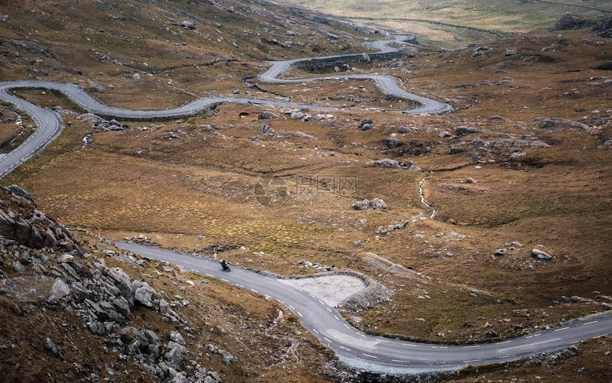 孤独的摩托车手在穿越爱尔兰科克县Beara半岛山谷时顺风下降希利山口图片