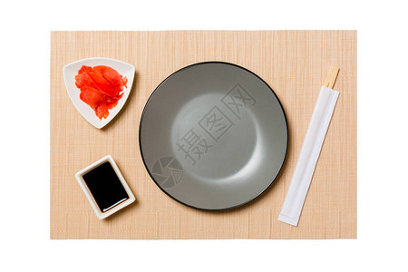 用筷子做寿司和酱油的空圆灰盘图片