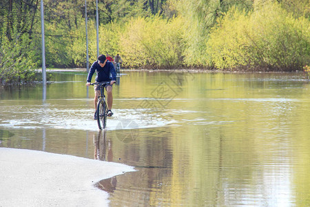 在春天的洪水中骑自行车河水溢出时在图片
