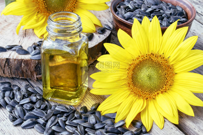 向日葵和种子在玻璃罐中向日葵油附近的木制背景上健康的食物和脂肪有图片