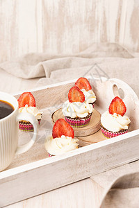 木制餐桌上加白奶油水果和浆果装饰的杯子蛋糕图片